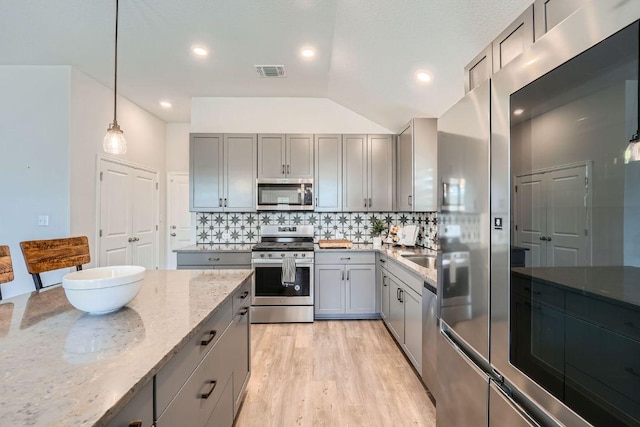 107 Lemuel Crawford Trl, Bastrop, TX 78602 - kitchen with appliances with stainless steel finishes, gray cabinets, light stone countertops, backsplash, and recessed lighting