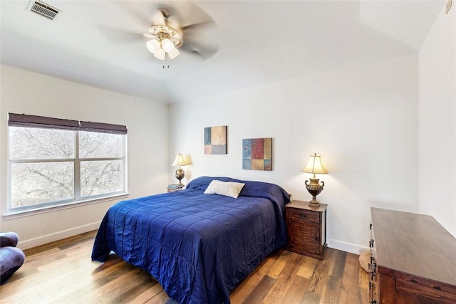 bedroom featuring ceiling fan, visible vents, baseboards, and wood finished floors