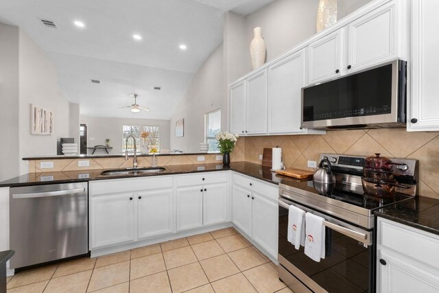 kitchen with backsplash, a peninsula, stainless steel appliances, a ceiling fan, and a sink