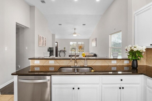 kitchen with a sink, white cabinetry, dark stone counters, dishwasher, and vaulted ceiling