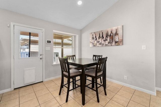 tiled dining room featuring baseboards and vaulted ceiling