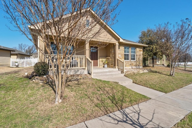 view of front of home with stone siding, a porch, a front lawn, and fence