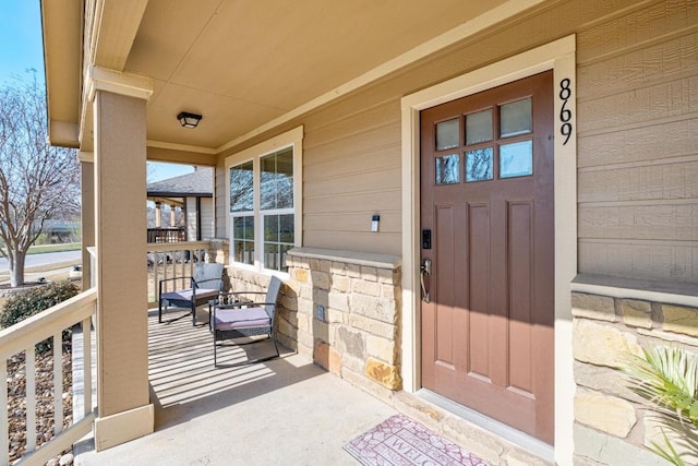 doorway to property with stone siding and covered porch