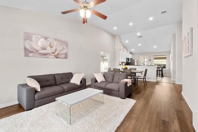 living area with lofted ceiling, dark wood-style floors, visible vents, and a healthy amount of sunlight