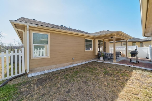 rear view of house featuring a lawn, a patio, and fence