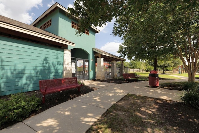 exterior space with stucco siding, fence, and a gate