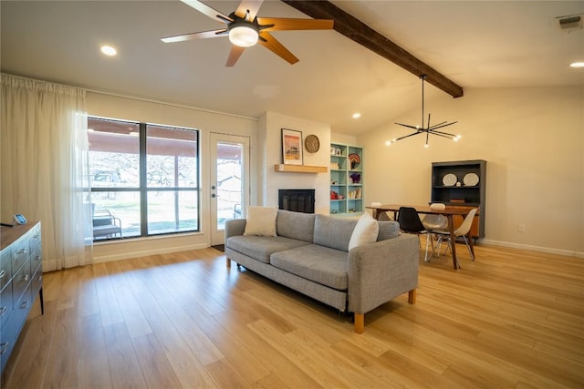 living area featuring visible vents, light wood-style floors, baseboards, a brick fireplace, and vaulted ceiling with beams