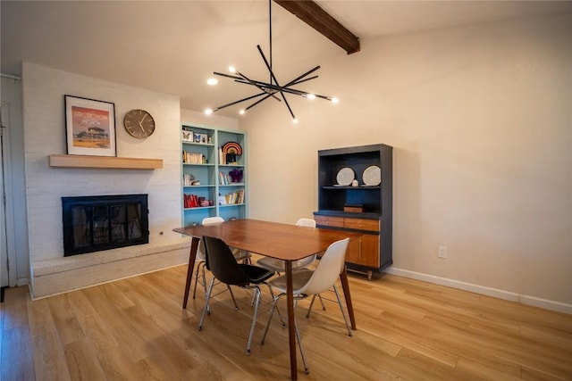 dining space featuring a brick fireplace, light wood-style flooring, vaulted ceiling with beams, and baseboards