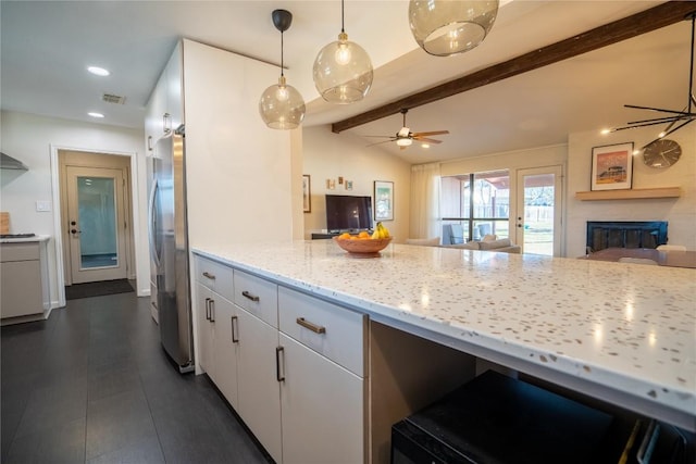 kitchen with vaulted ceiling with beams, open floor plan, light stone counters, a fireplace, and freestanding refrigerator