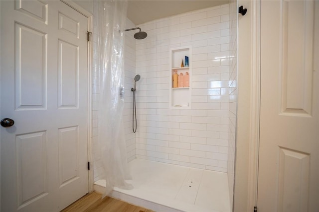 bathroom featuring tiled shower and wood finished floors