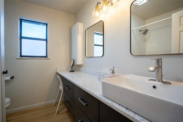 full bathroom with baseboards, plenty of natural light, toilet, and wood finished floors