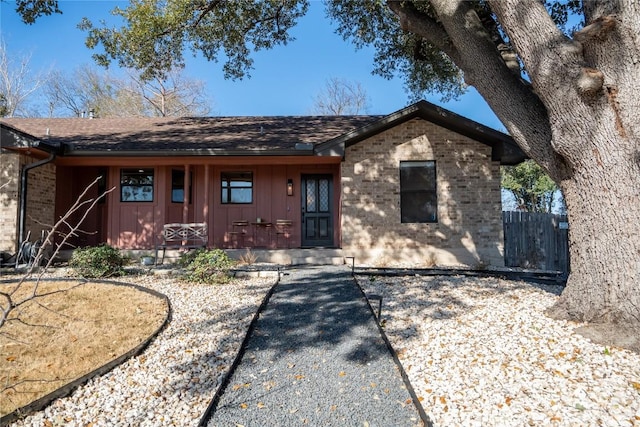 ranch-style house featuring brick siding, covered porch, and board and batten siding