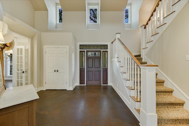 foyer with stairs, a high ceiling, and baseboards