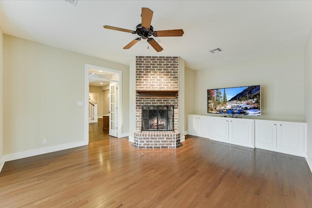 unfurnished living room featuring visible vents, a ceiling fan, wood finished floors, a fireplace, and baseboards