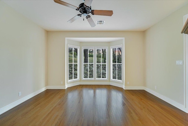 spare room with visible vents, baseboards, wood finished floors, and a ceiling fan