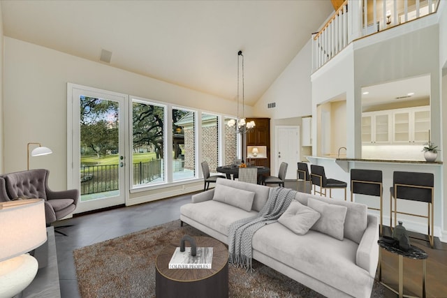 living area featuring a notable chandelier, visible vents, and high vaulted ceiling