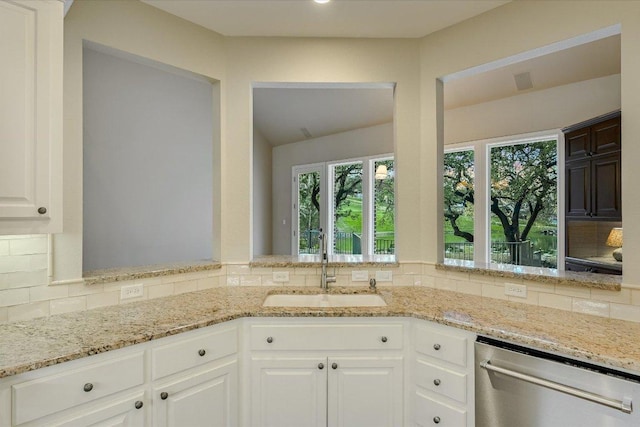 kitchen featuring dishwasher, light stone countertops, backsplash, and a sink