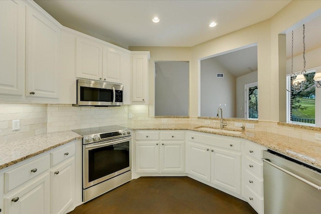 kitchen with a sink, backsplash, white cabinetry, stainless steel appliances, and light stone countertops