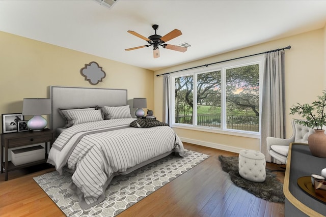 bedroom featuring visible vents, ceiling fan, baseboards, and wood finished floors