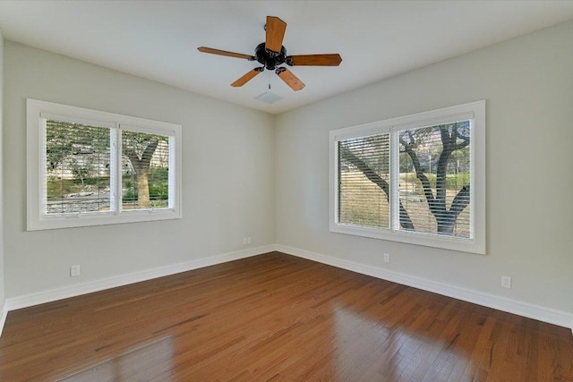 spare room featuring ceiling fan, visible vents, baseboards, and wood finished floors