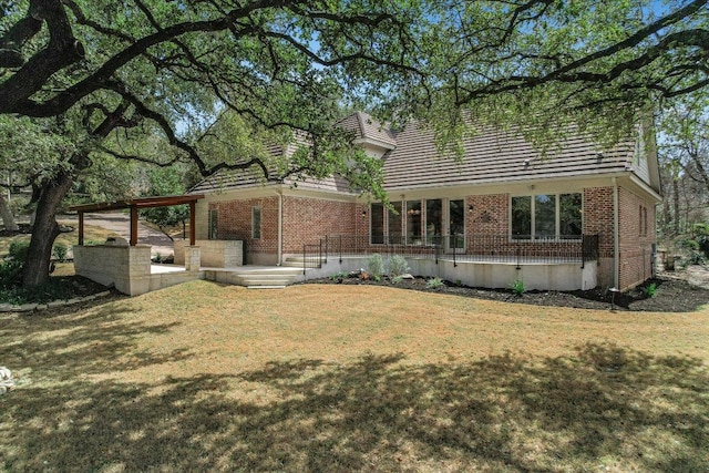 rear view of house featuring brick siding and a lawn