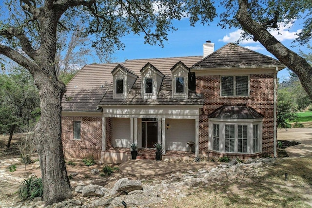 view of front of property with brick siding, covered porch, and a chimney