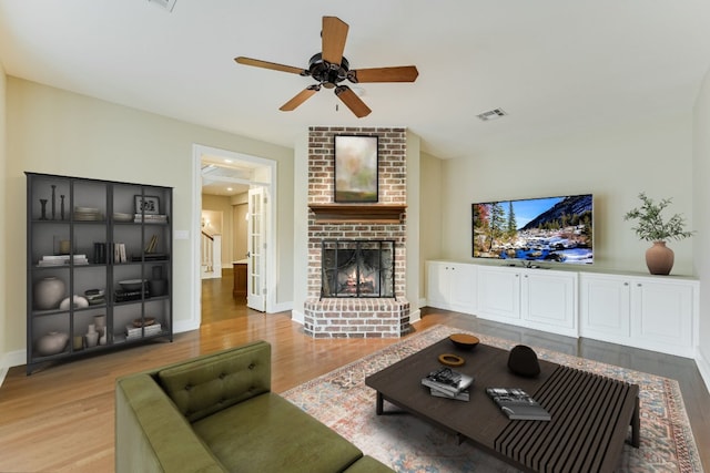 living area with visible vents, a fireplace, baseboards, and wood finished floors