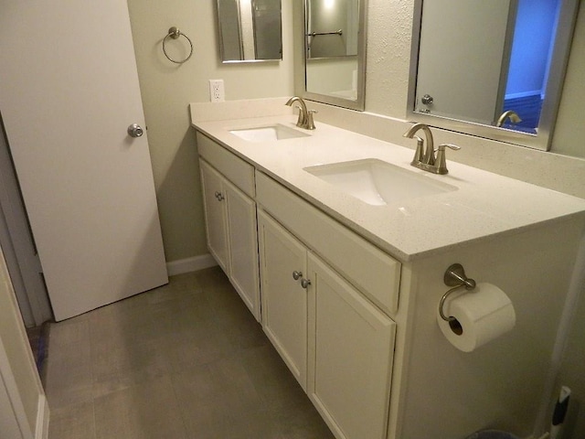 bathroom with double vanity, baseboards, and a sink