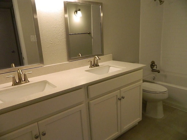 bathroom featuring double vanity, washtub / shower combination, toilet, and a sink