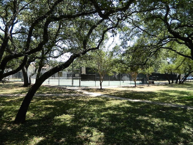 view of home's community featuring a yard, a tennis court, and fence