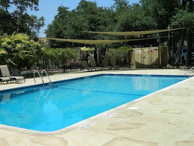 pool with a patio area and fence