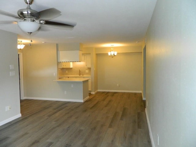 unfurnished living room featuring a sink, baseboards, wood finished floors, and ceiling fan with notable chandelier