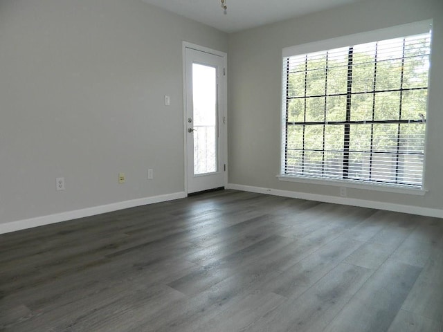 unfurnished room featuring baseboards and dark wood-type flooring