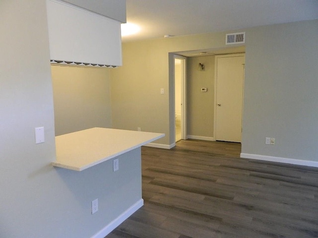 spare room featuring visible vents, baseboards, and dark wood-style flooring