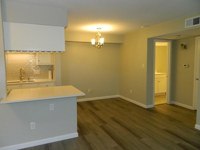 interior space with tasteful backsplash, visible vents, dark wood-type flooring, light countertops, and a sink