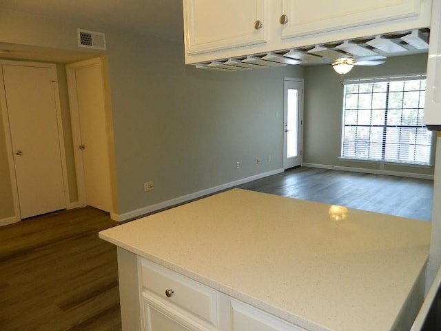 kitchen with visible vents, baseboards, white cabinets, and dark wood-style flooring