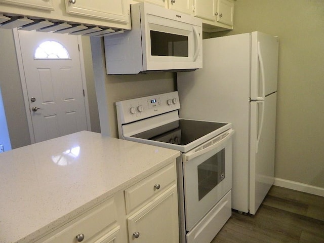 kitchen featuring light stone counters, dark wood finished floors, white cabinetry, white appliances, and baseboards