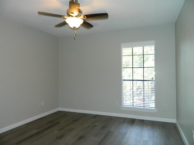 empty room featuring dark wood-type flooring, plenty of natural light, a ceiling fan, and baseboards