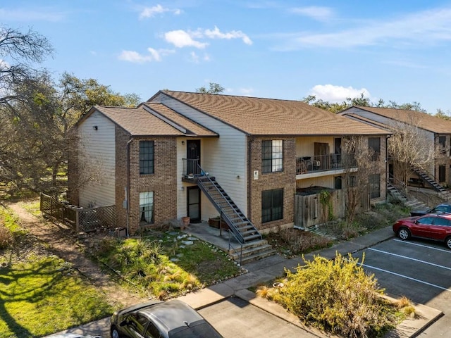 view of property featuring stairway and uncovered parking