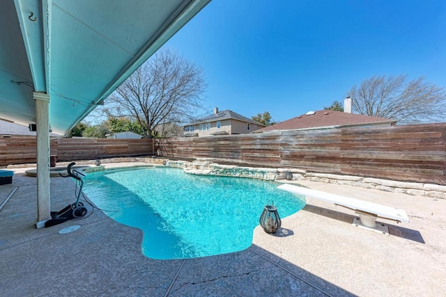 view of swimming pool featuring a diving board, a fenced in pool, a patio, and a fenced backyard