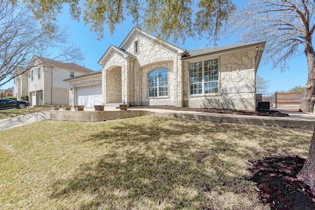 view of front of property featuring stone siding, an attached garage, concrete driveway, and a front lawn