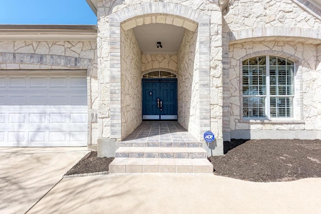 property entrance featuring an attached garage and stone siding