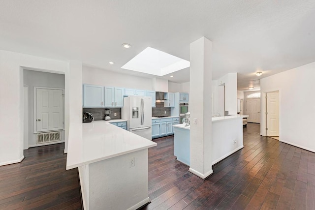 1000 Rutgers Dr, Pflugerville, TX 78660 - kitchen featuring white refrigerator with ice dispenser, a peninsula, wall chimney range hood, light countertops, and recessed lighting