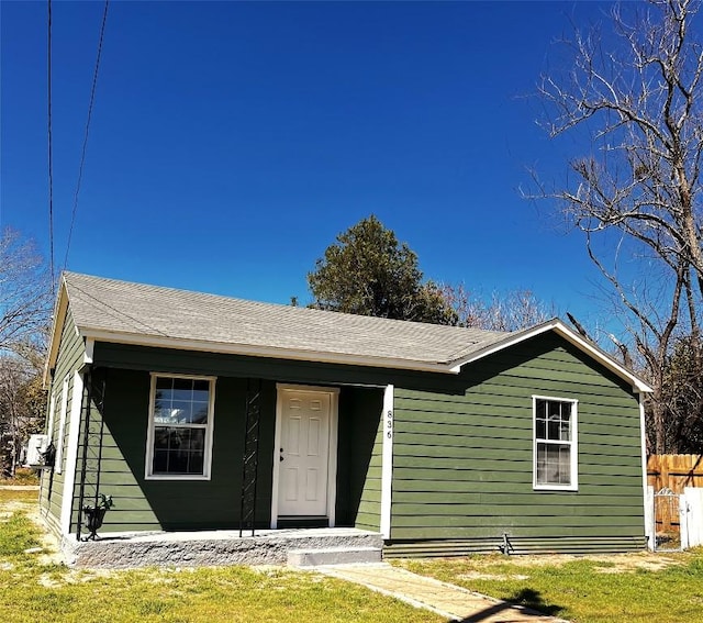 view of front of home featuring a porch, fence, and roof with shingles