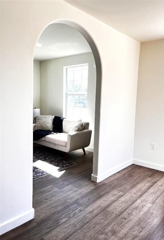 living room with arched walkways and wood finished floors