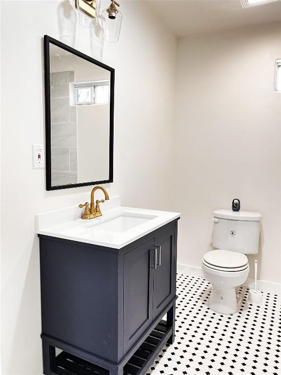 half bathroom with tile patterned flooring, toilet, vanity, and baseboards