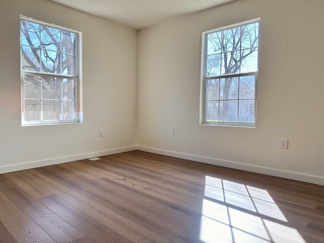 spare room with dark wood-style floors, plenty of natural light, and baseboards