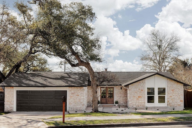 mid-century home with an attached garage, french doors, driveway, and roof with shingles