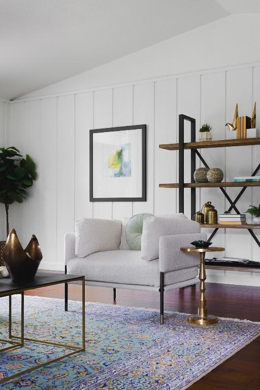 living area with a decorative wall, wood finished floors, and vaulted ceiling