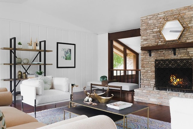 living room with a stone fireplace, hardwood / wood-style flooring, and lofted ceiling